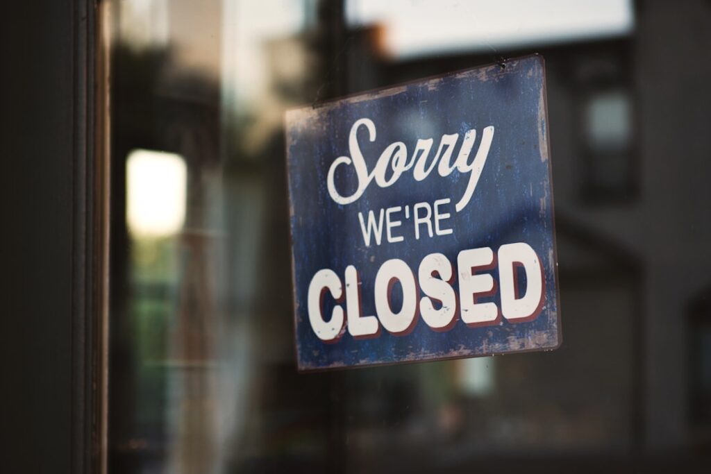 A "Sorry we're closed" sign hanging on a glass storefront door