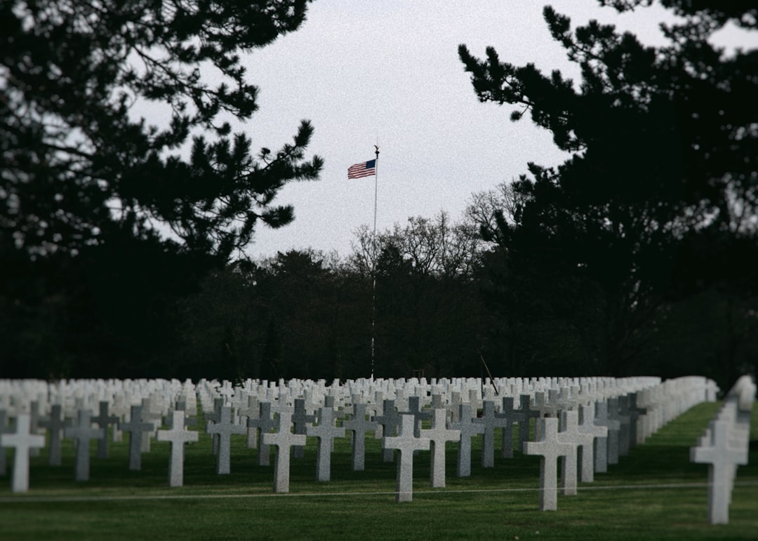 White grave markers and an American flag in a military cemetery, honoring Memorial Day 2027
